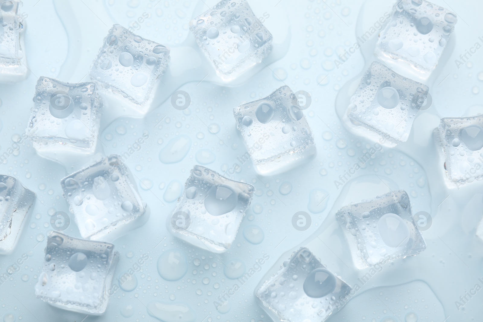 Photo of Crystal clear ice cubes on light blue background, flat lay