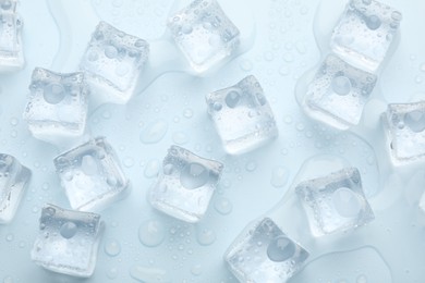 Crystal clear ice cubes on light blue background, flat lay