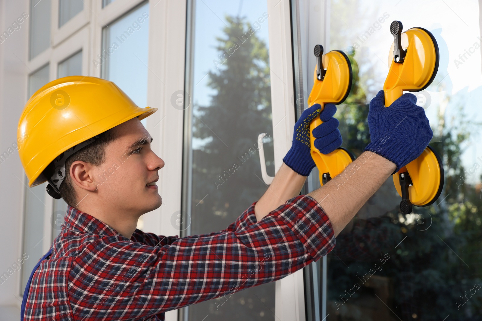 Photo of Worker using suction lifters during plastic window installation indoors