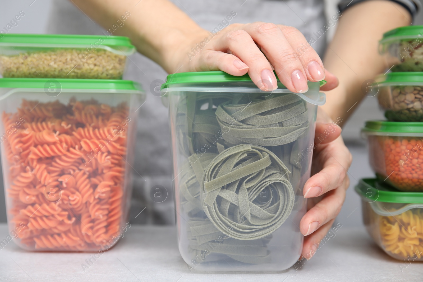 Photo of Woman with plastic containers filled of food products at light table indoors, closeup