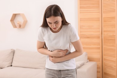 Photo of Young woman suffering from stomach pain at home