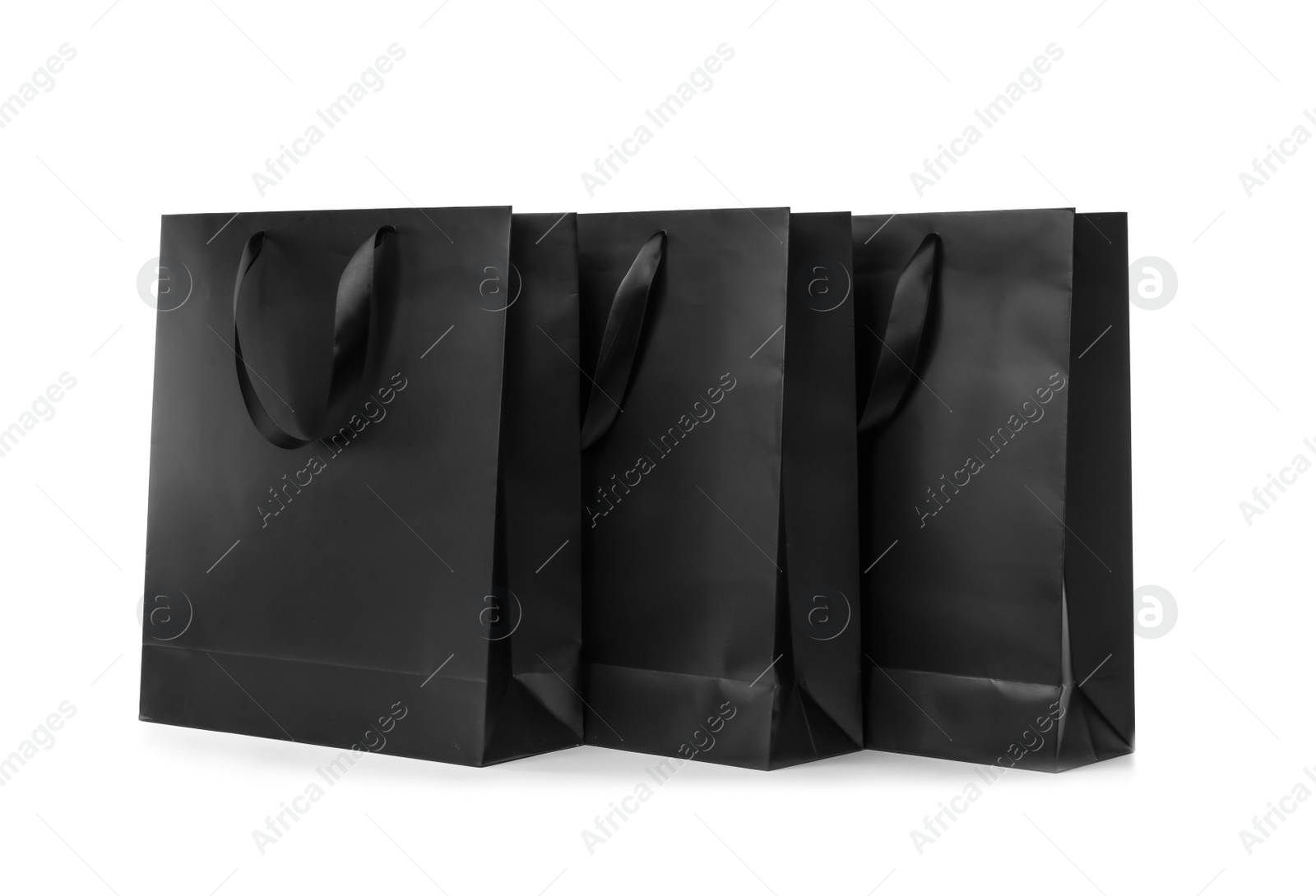 Photo of Paper shopping bags with ribbon handles on white background. Mockup for design