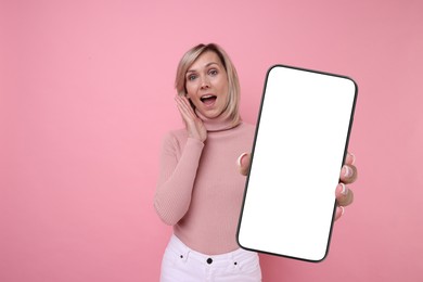 Image of Woman showing mobile phone with blank screen on pink background. Mockup for design