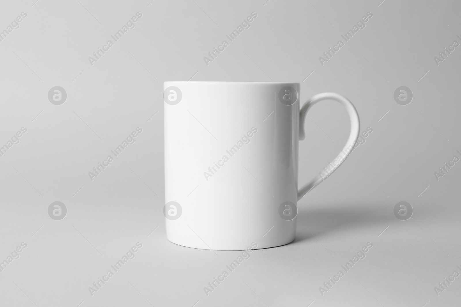 White ceramic mug on light grey background Photo of White ceramic mug on light grey background