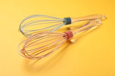 Two whisks on yellow background, closeup. Kitchen tool