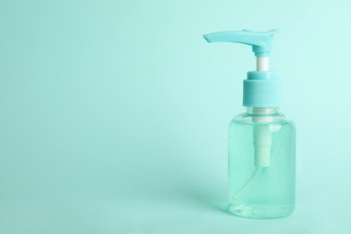 Photo of Dispenser bottle with antiseptic gel on light blue background. Space for text