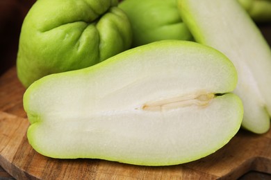 Photo of Cut and whole chayote on wooden board, closeup