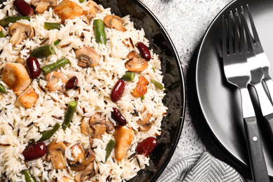Photo of Delicious rice pilaf with chicken and vegetables on grey table, closeup