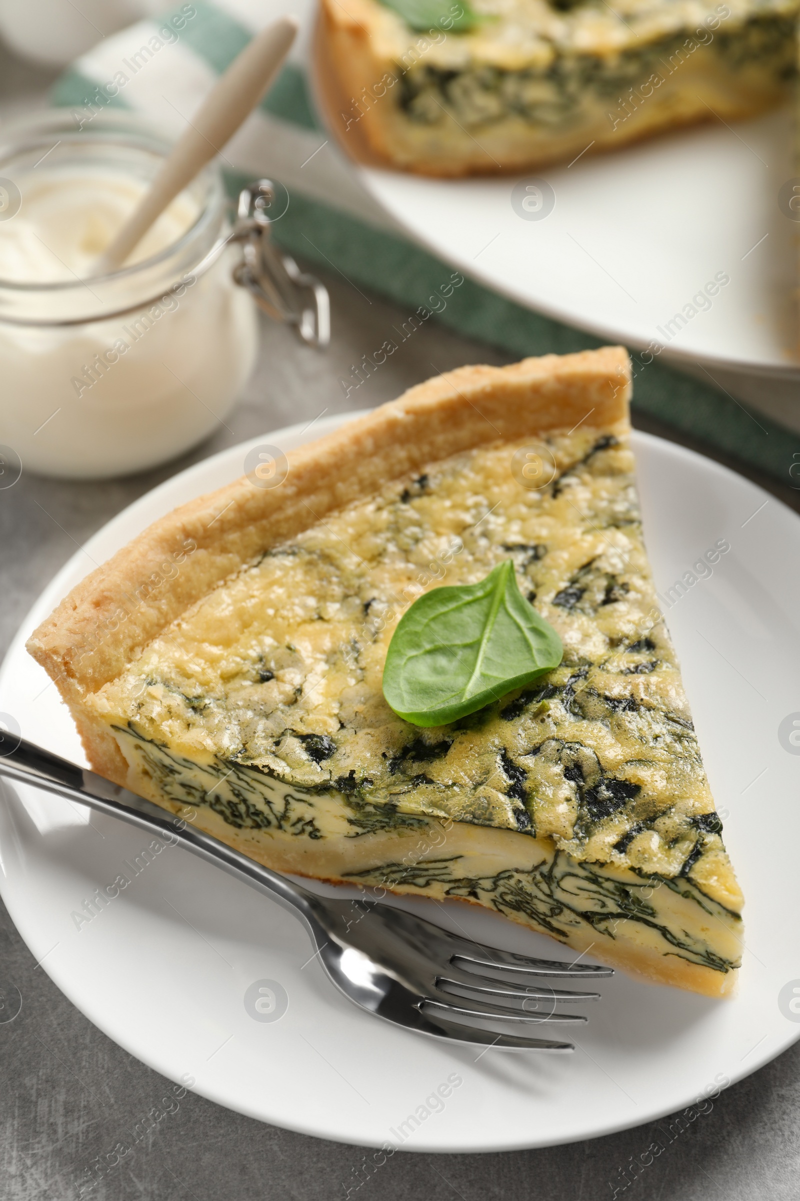 Photo of Piece of delicious homemade spinach pie on grey table, closeup