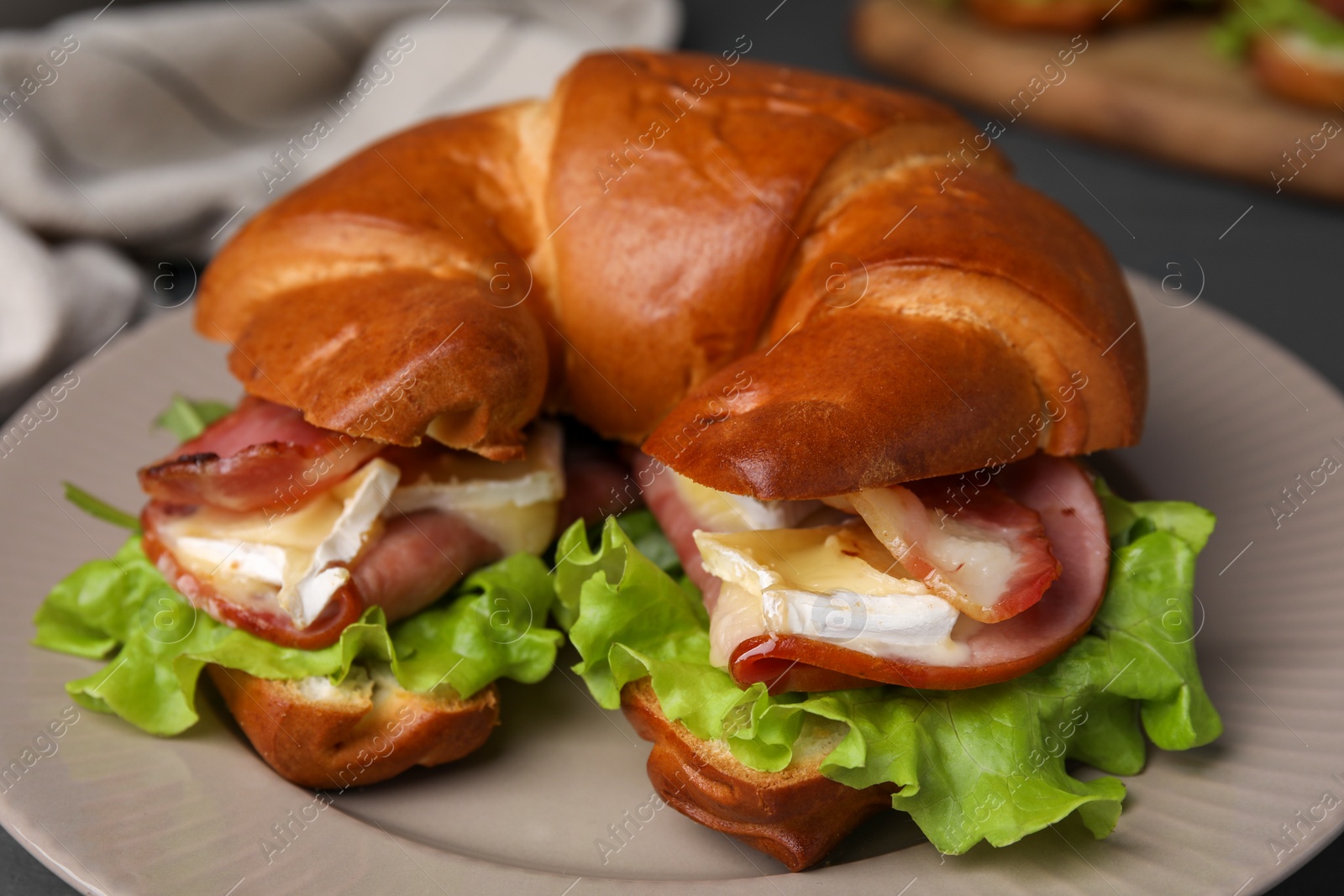 Photo of Tasty crescent roll with brie cheese, ham and bacon on table, closeup