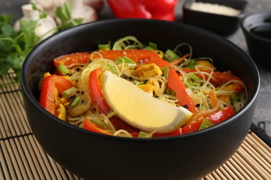 Photo of Stir-fry. Delicious cooked noodles with chicken and vegetables in bowl on table, closeup