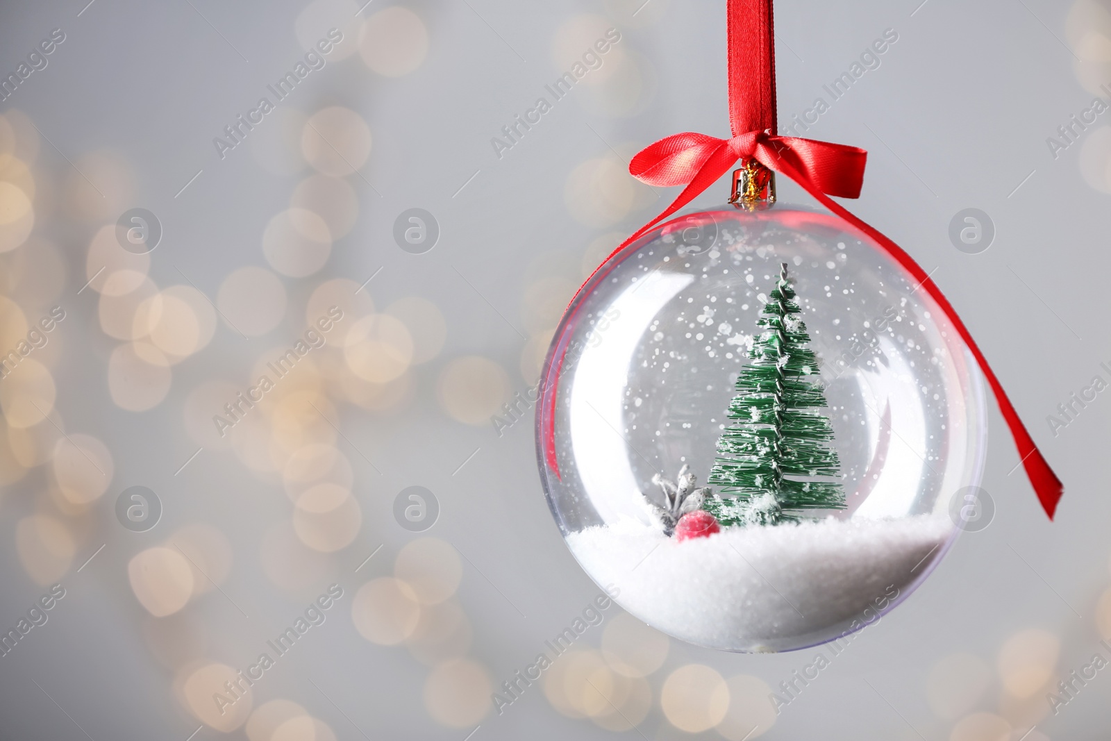 Photo of Decorative snow globe against blurred festive lights, closeup. Space for text