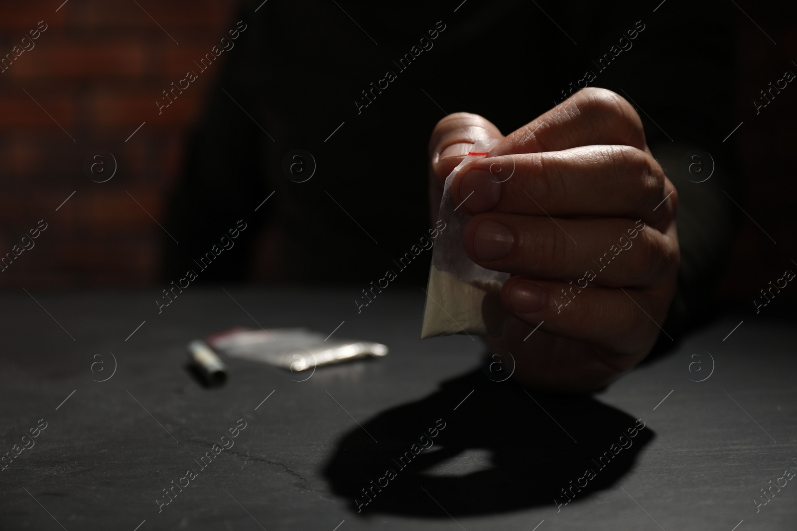 Photo of Drug addiction. Man with plastic bag of cocaine at grey table, selective focus