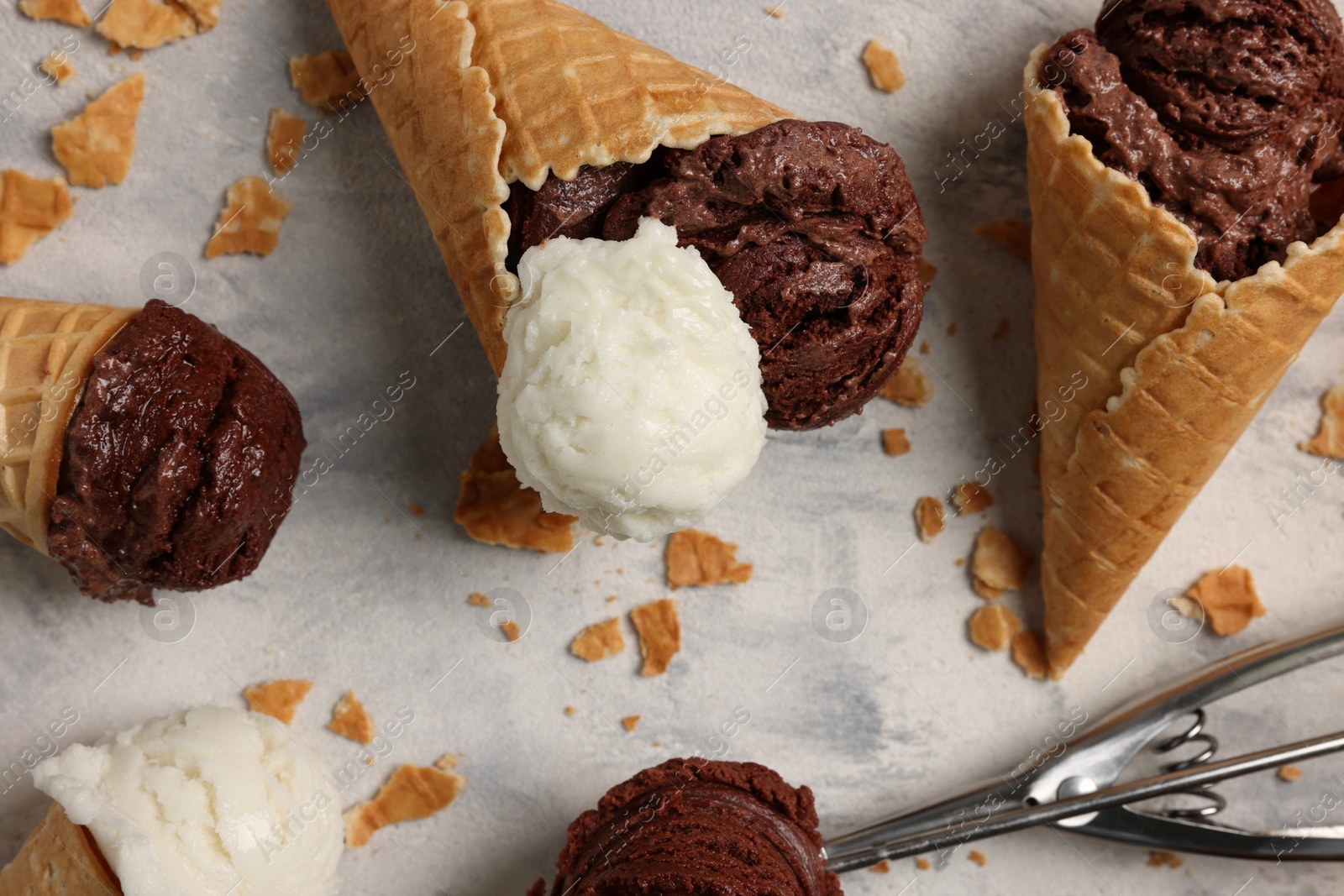 Photo of Composition with tasty ice cream scoops in waffle cones on light textured table, above view