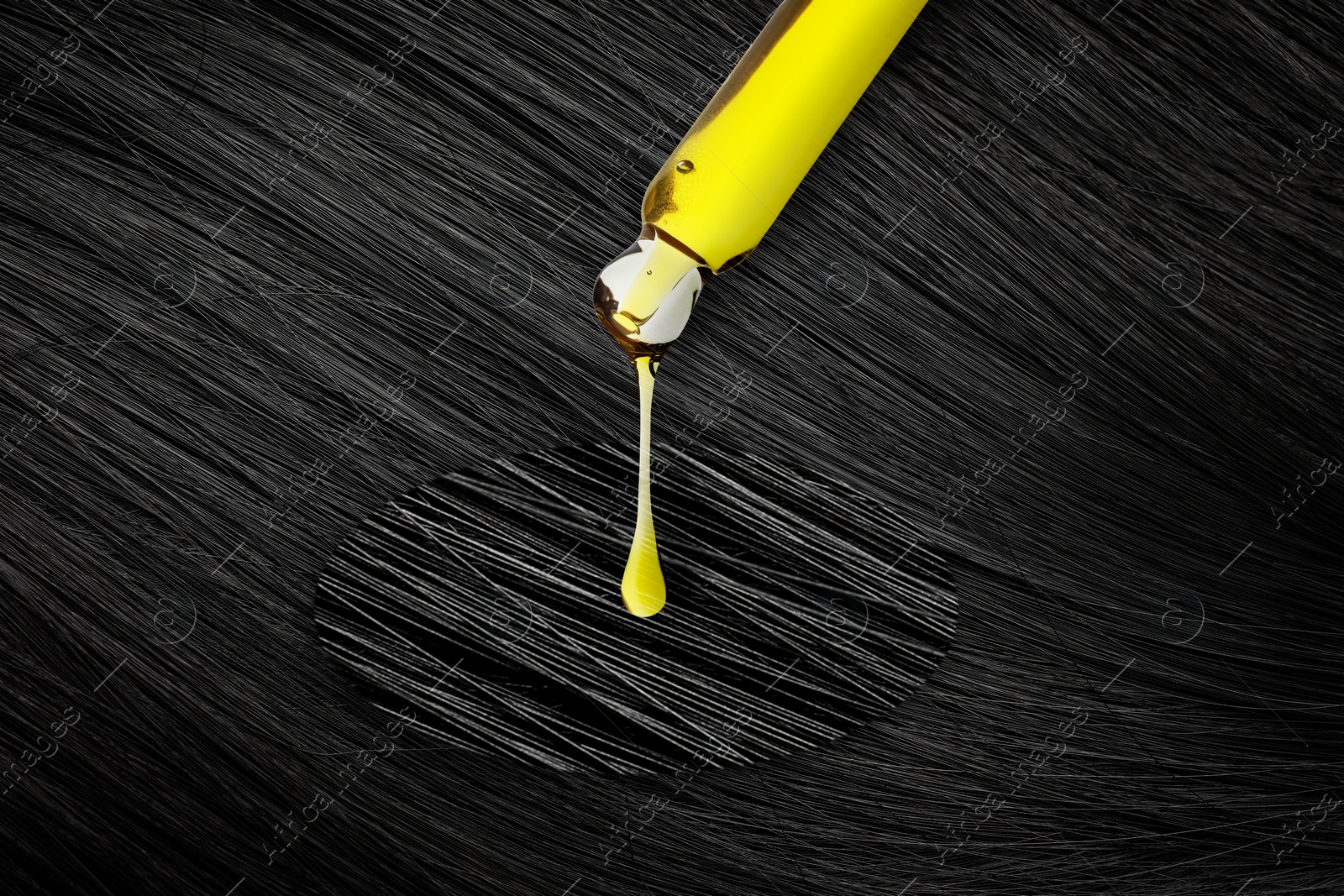 Image of Dripping cosmetic oil from pipette onto brunette hair in zoomed area