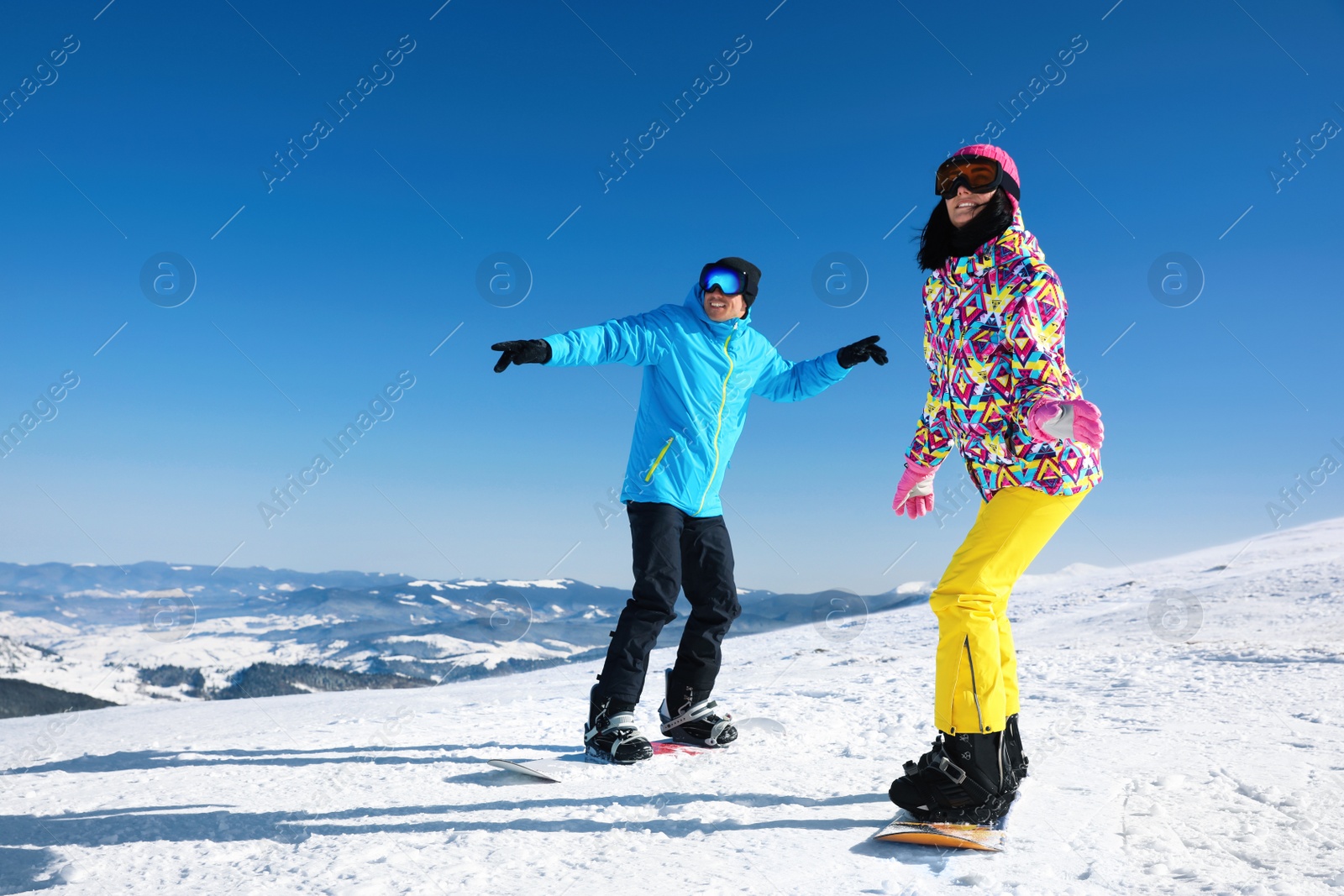 Photo of Couple snowboarding on snowy hill. Winter vacation