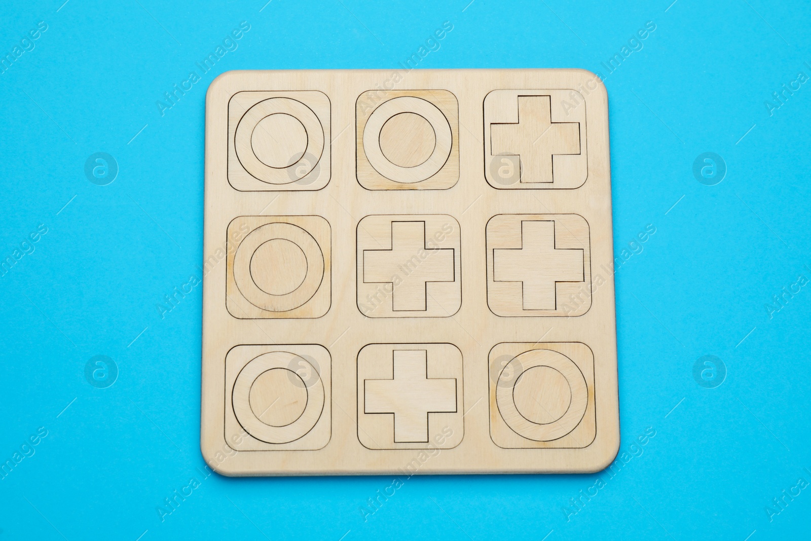 Photo of Tic tac toe set on light blue background, top view