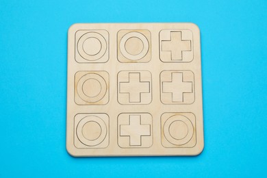 Tic tac toe set on light blue background, top view
