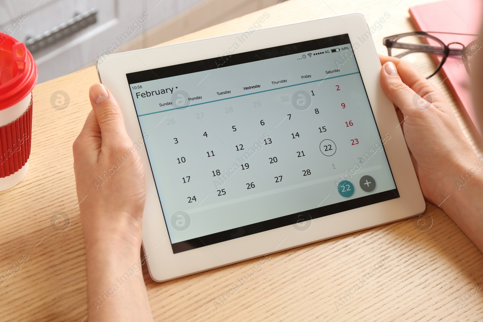 Photo of Woman using calendar app on tablet in office, closeup