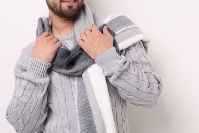 Smiling man in warm scarf on light background, closeup