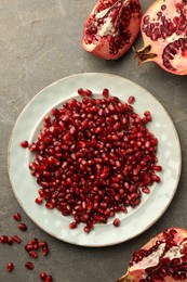 Photo of Tasty ripe pomegranate and grains on grey table, flat lay