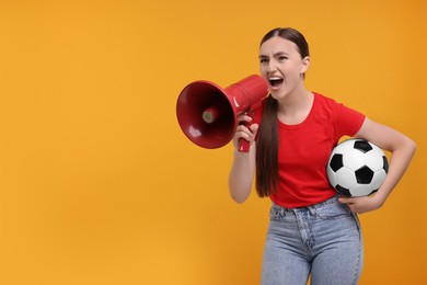 Photo of Sports fan with soccer ball shouting in megaphone on orange background. Space for text