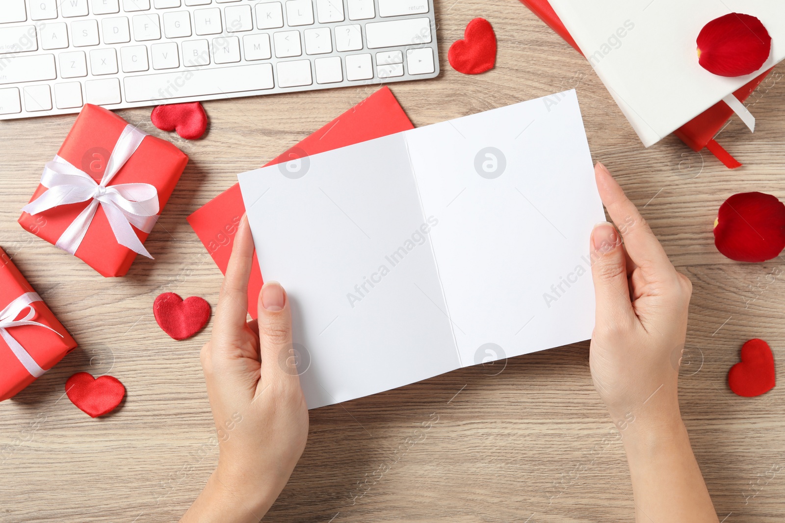 Photo of Woman with blank greeting card above wooden table in office, top view. Valentine's day celebration