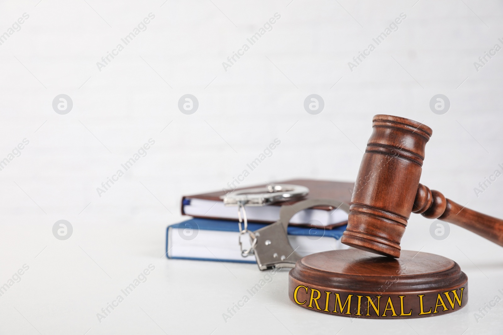 Image of Gavel, handcuffs and books on white table, space for text. Criminal law concept 