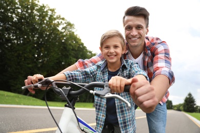 Dad teaching son to ride bicycle outdoors