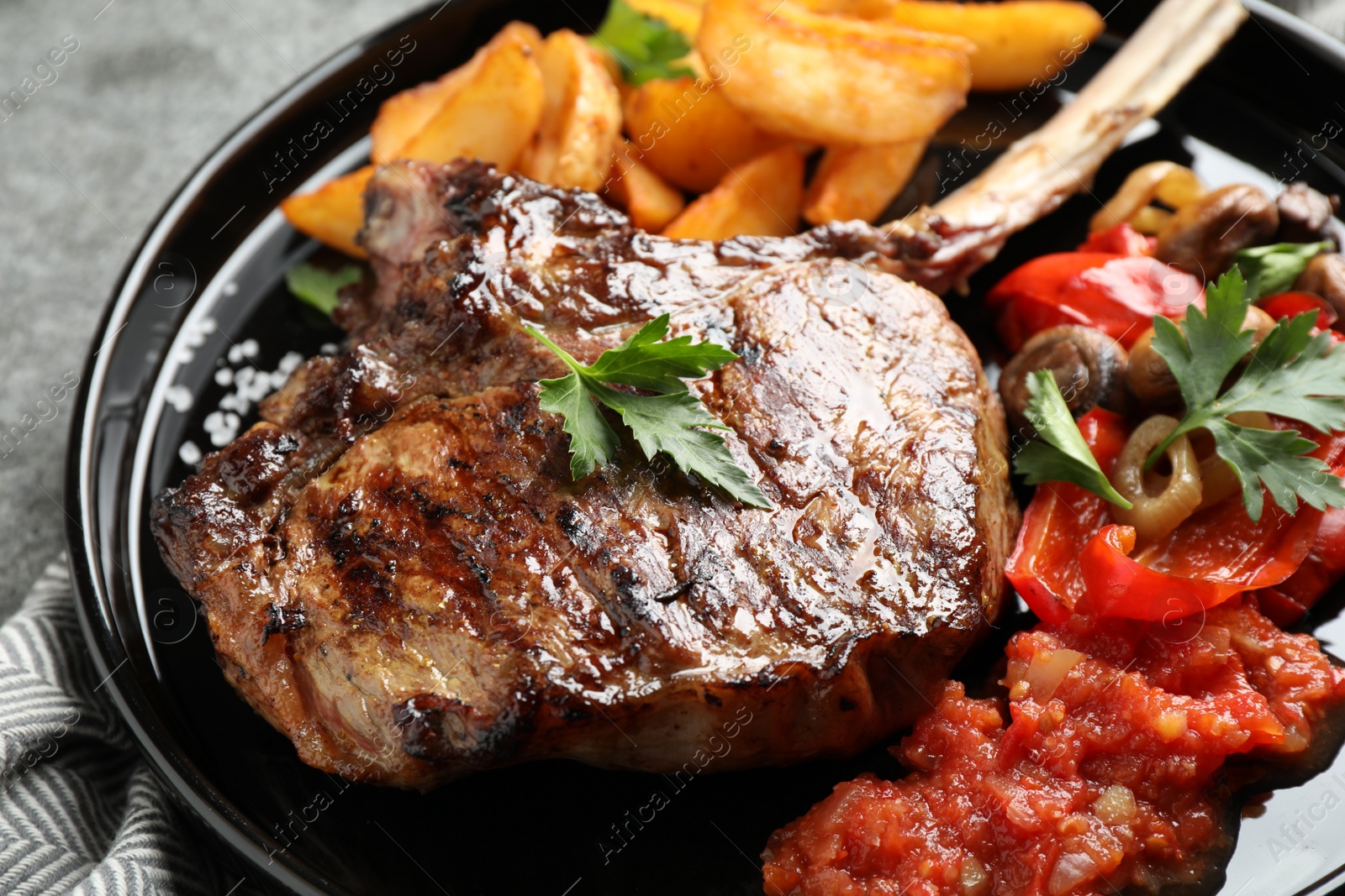 Photo of Delicious grilled ribeye served on grey table, closeup