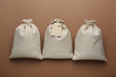 Photo of Tied burlap bags on brown background, flat lay