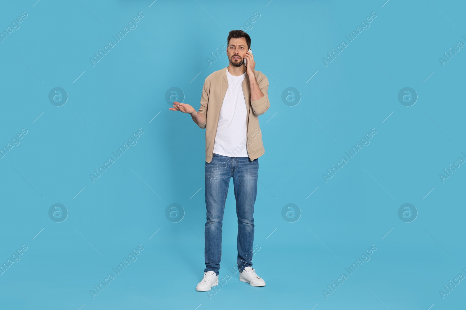 Photo of Man talking on phone against light blue background