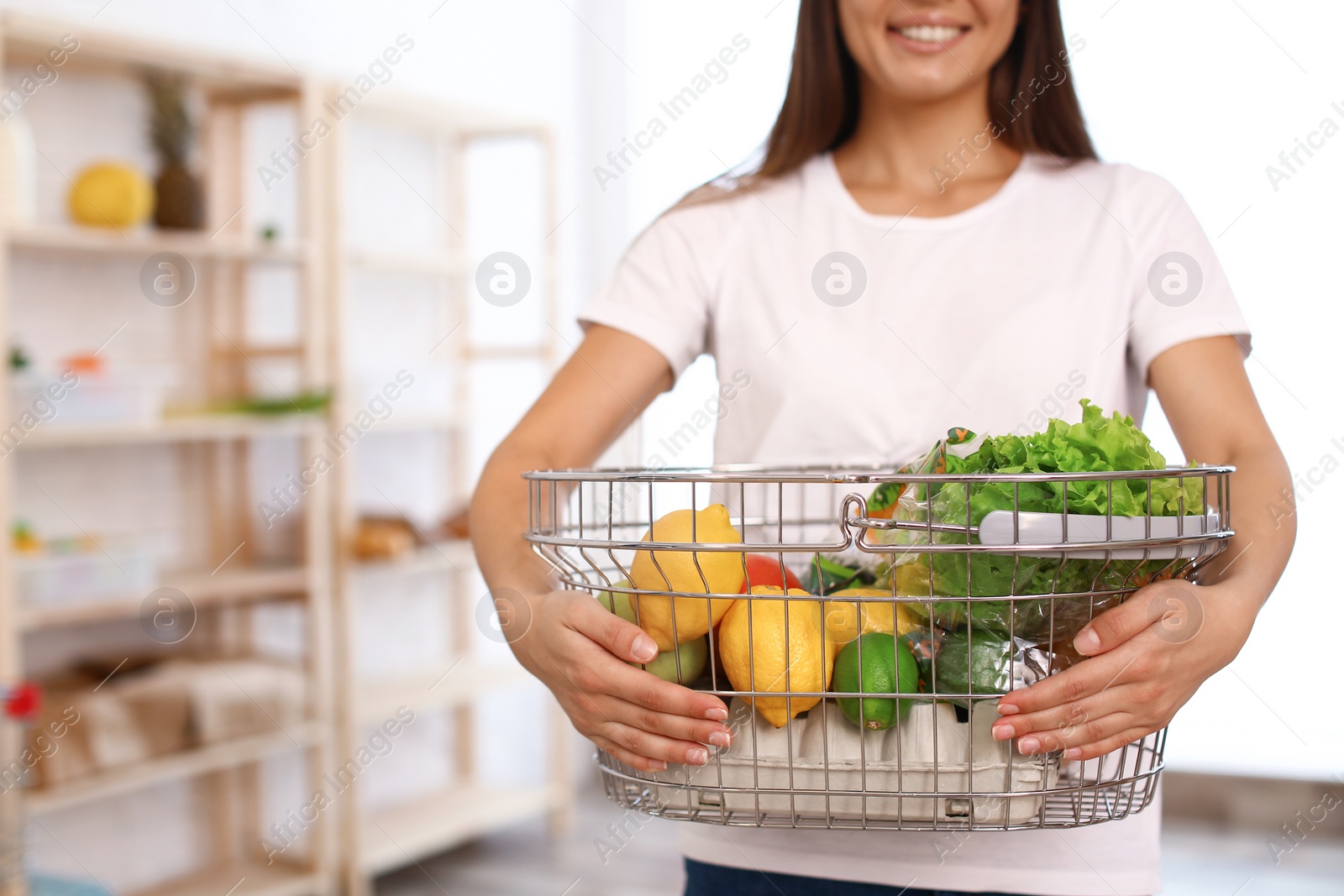 Photo of Woman with shopping basket full of products in grocery store, closeup