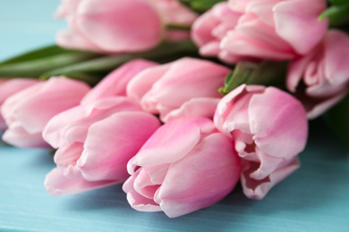 Photo of Beautiful pink spring tulips on light blue background, closeup