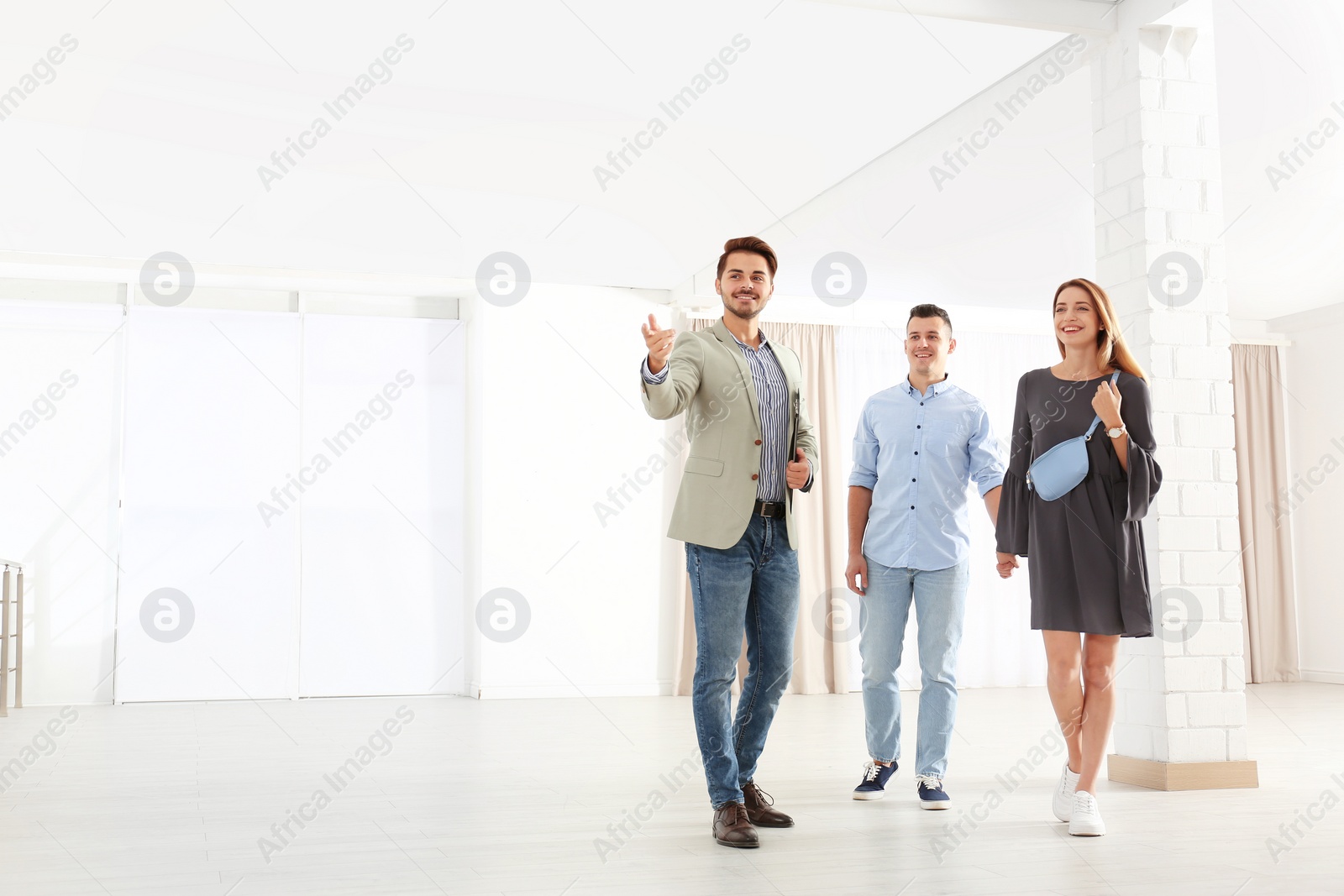 Photo of Real estate agent showing new apartment to young couple. Space for text