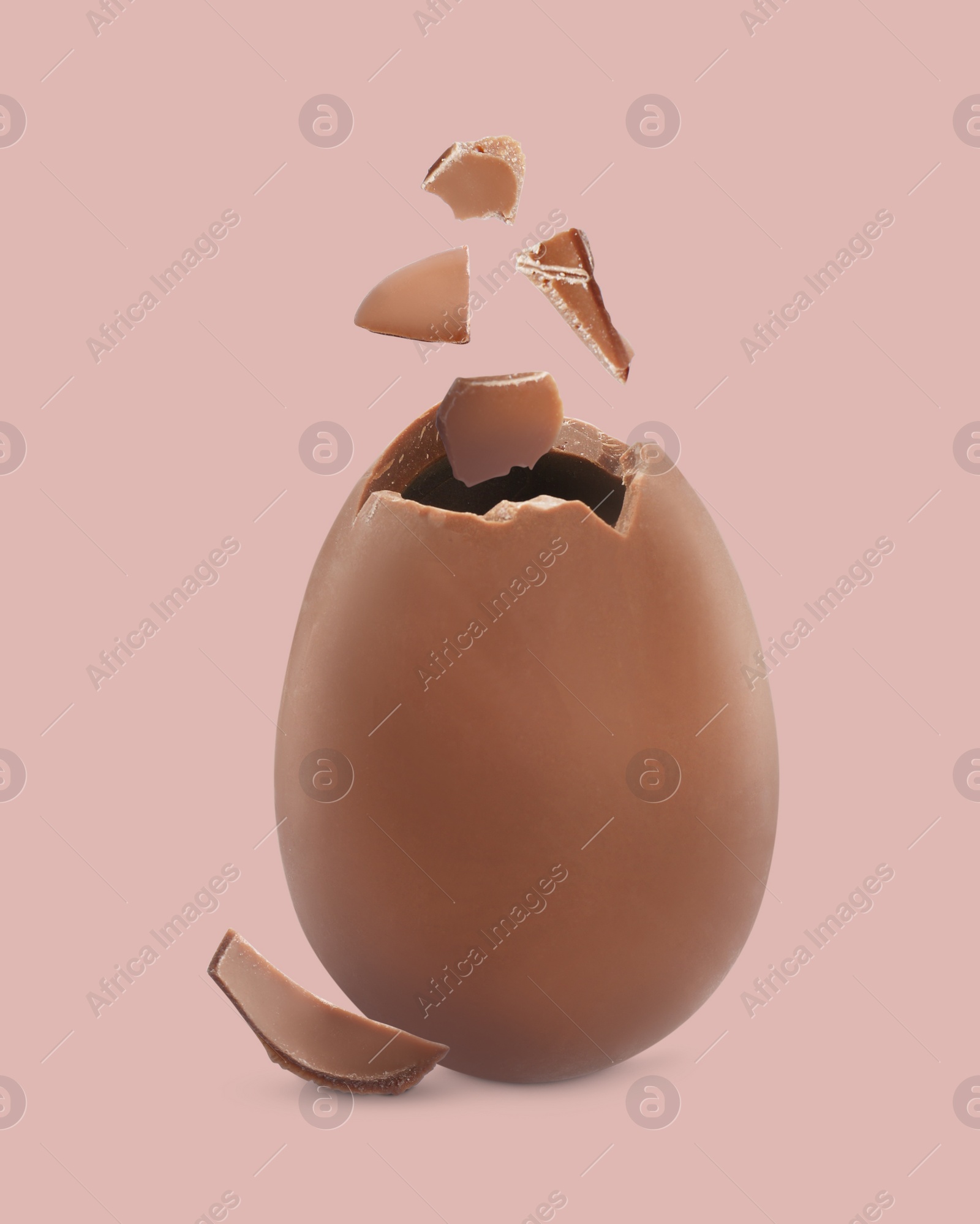 Image of Exploded milk chocolate egg on dusty pink background