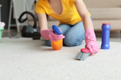 Young woman cleaning carpet at home