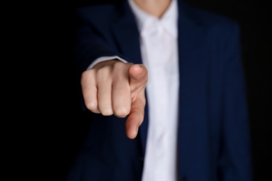 Photo of Businesswoman pointing at something on black background, closeup. Finger gesture
