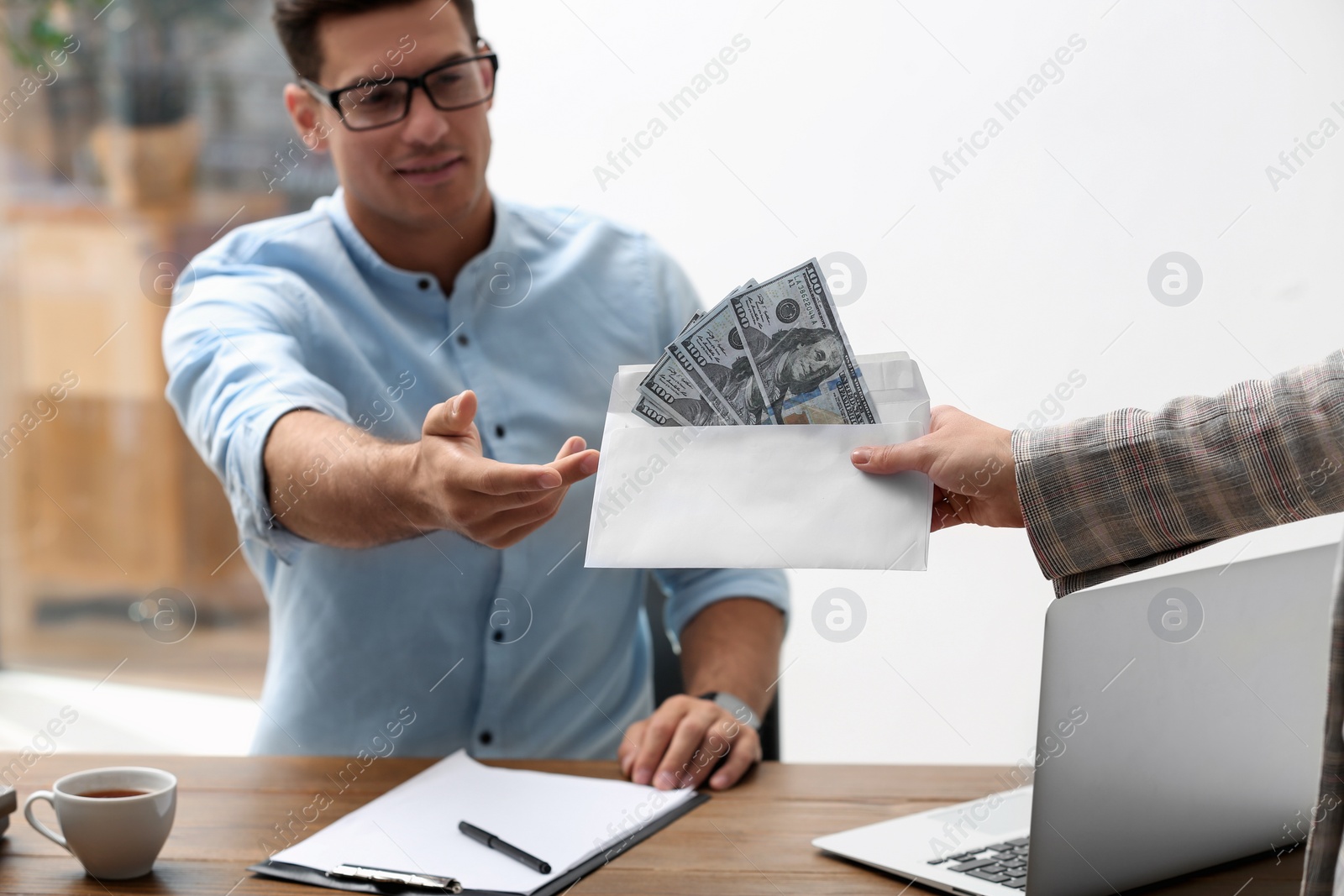 Photo of Woman giving bribe money to man at table, closeup