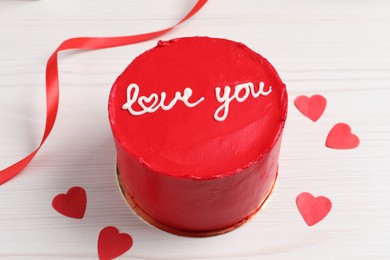 Photo of Bento cake with text Love You, ribbon and paper hearts on white wooden table. St. Valentine's day surprise