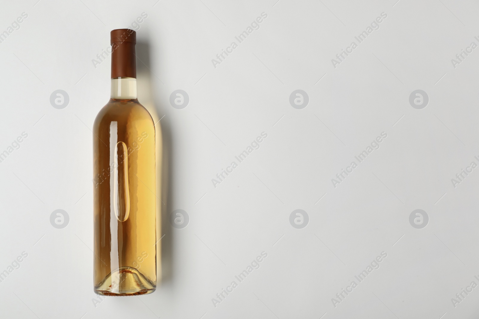 Photo of Bottle of expensive white wine on light background, top view