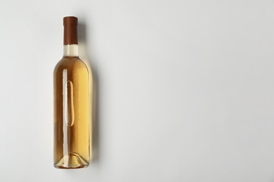 Bottle of expensive white wine on light background, top view