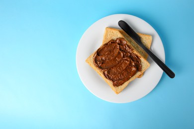 Photo of Tasty toast with chocolate paste on light blue background, top view. Space for text