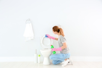 Photo of Woman cleaning toilet bowl in bathroom