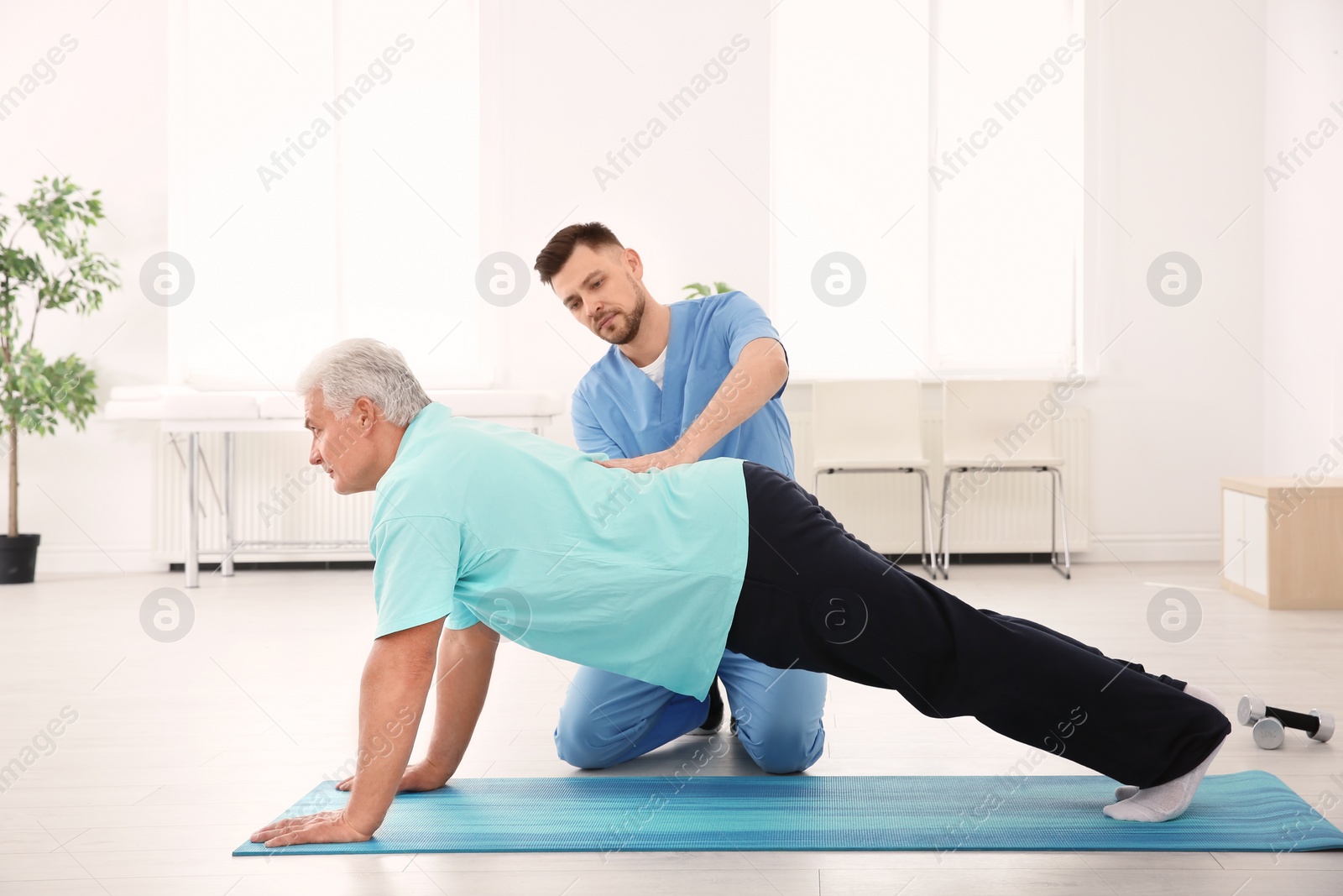 Photo of Young physiotherapist working with senior patient in clinic