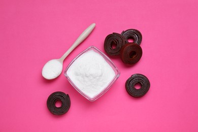 Photo of Sweet powdered fructose and fruit leather rolls on pink background, flat lay