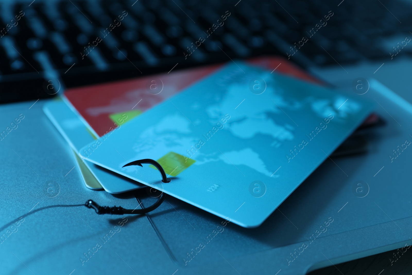 Photo of Fishing hook with credit cards on laptop, closeup. Cyber crime
