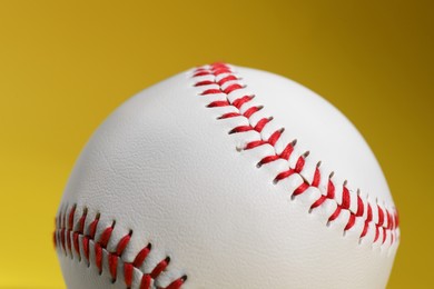 Photo of One baseball ball on yellow background, closeup