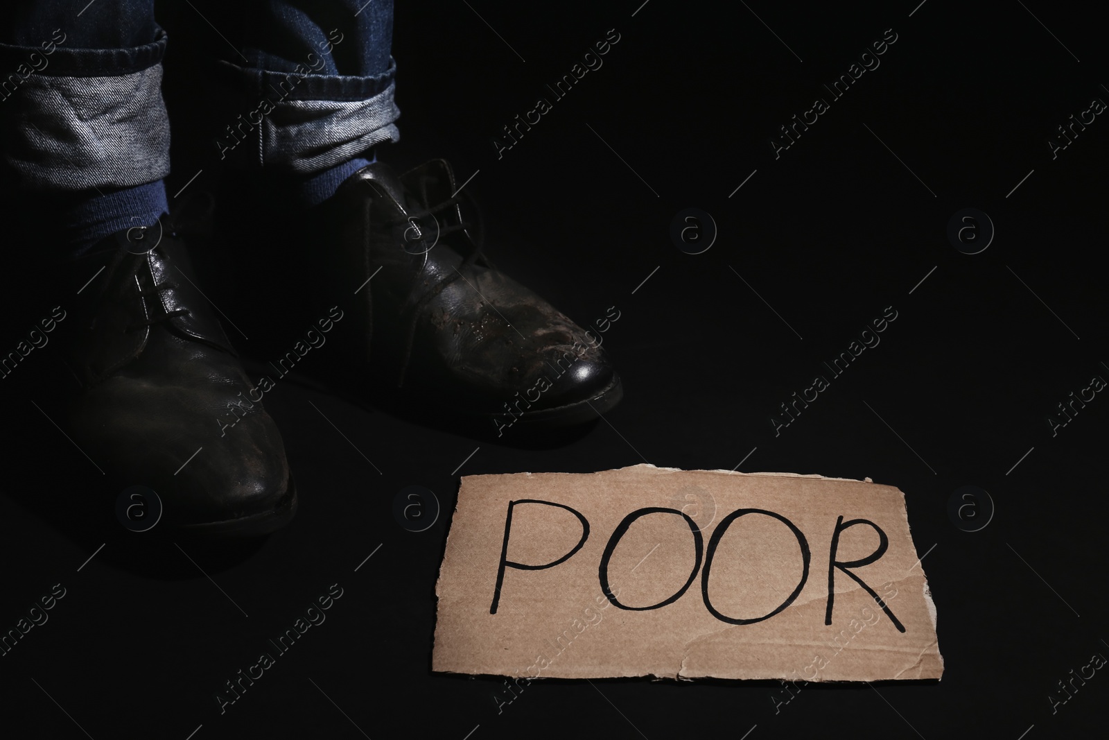 Photo of Man standing near carton sign with word POOR on dark background, closeup