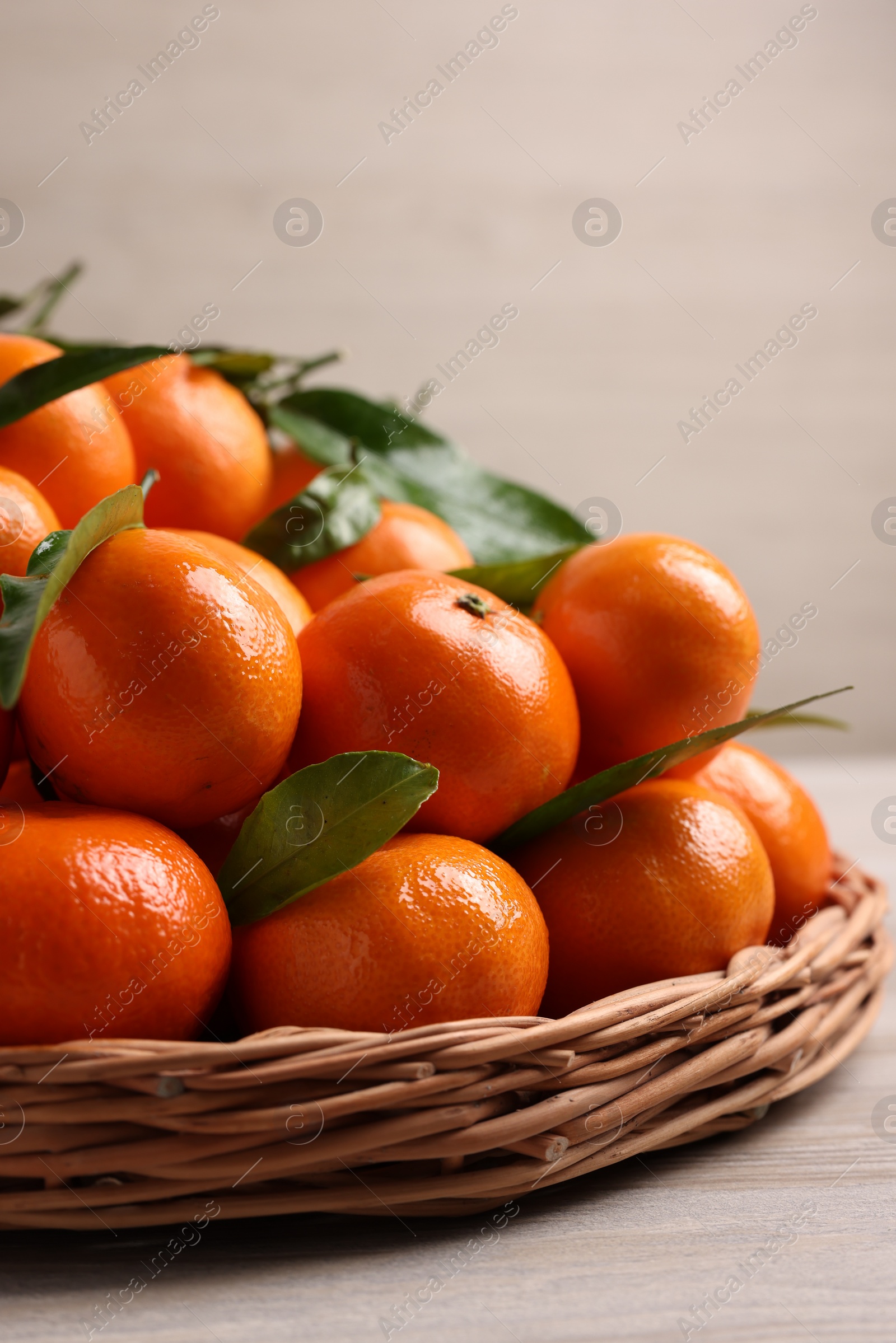 Photo of Fresh ripe juicy tangerines and green leaves on white wooden table